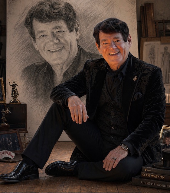 Alan Watson QSM seated beside a sketched portrait of himself